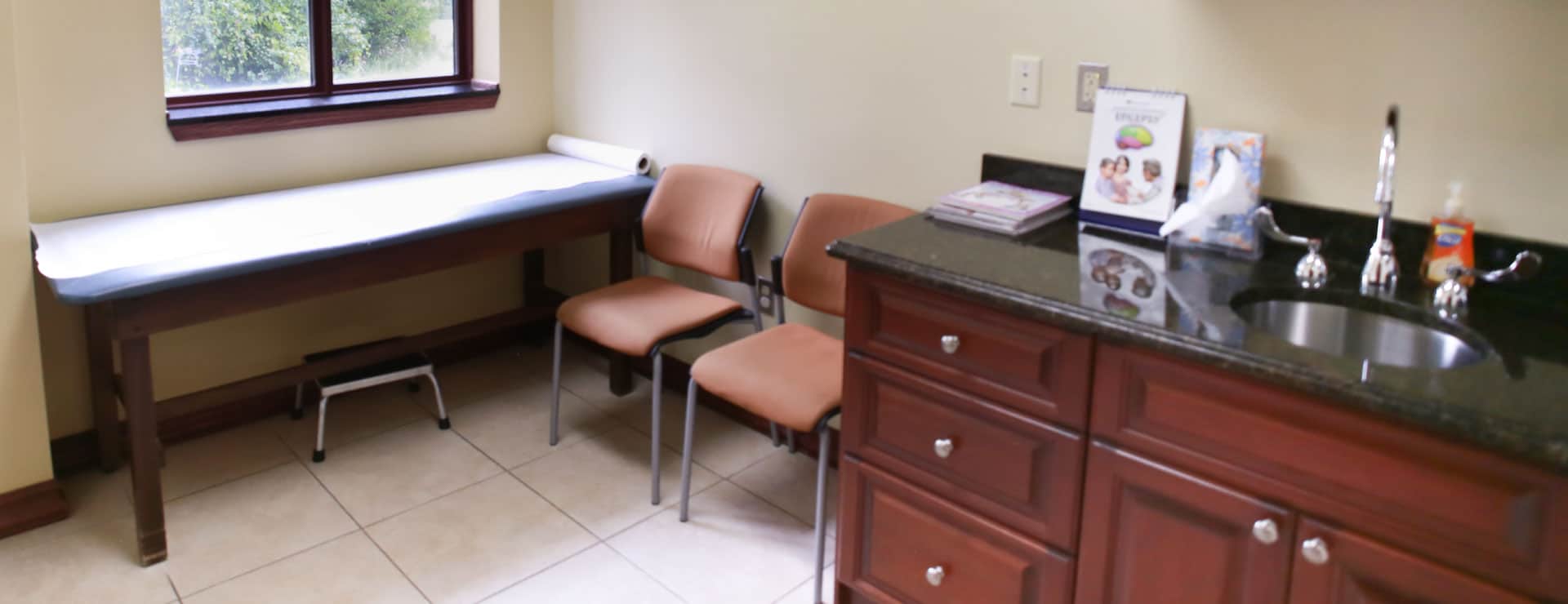 Examination room with an exam table, two chairs and a sink