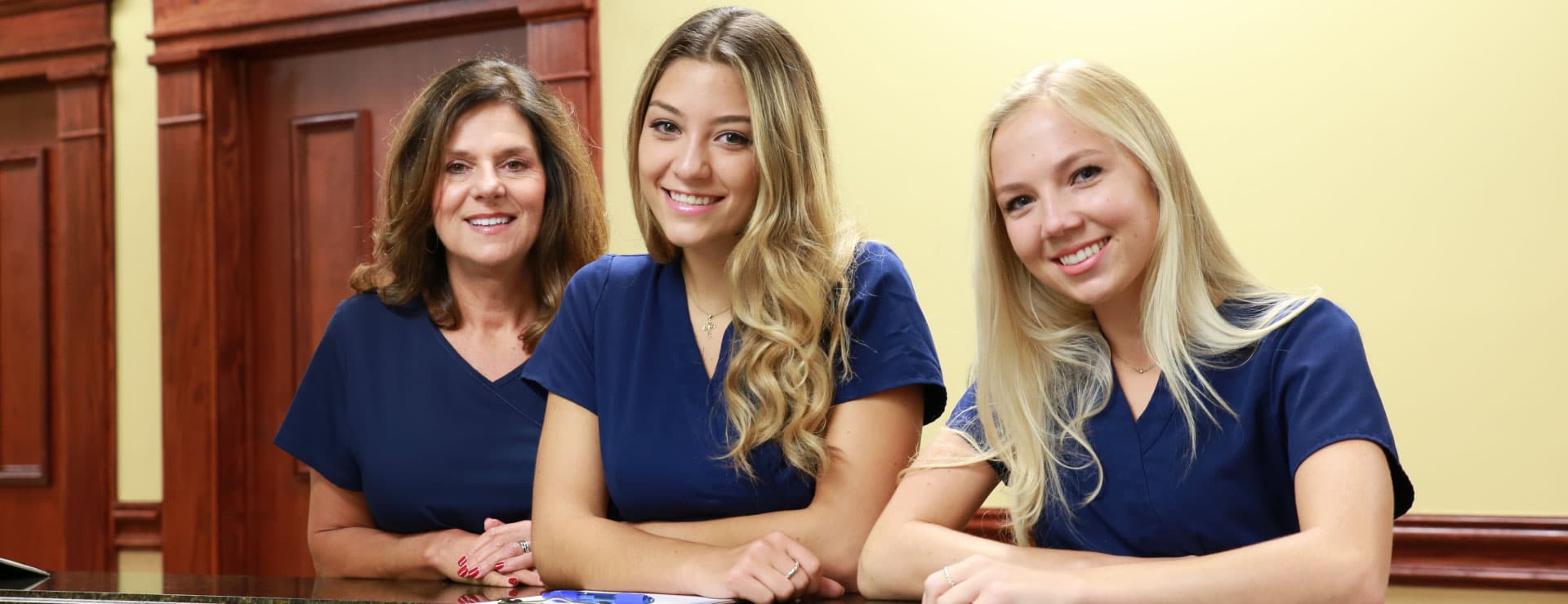 Three clinic staff members pictured at the reception desk